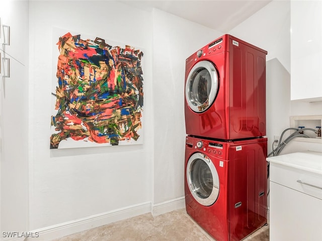 washroom featuring cabinets, stacked washing maching and dryer, and sink