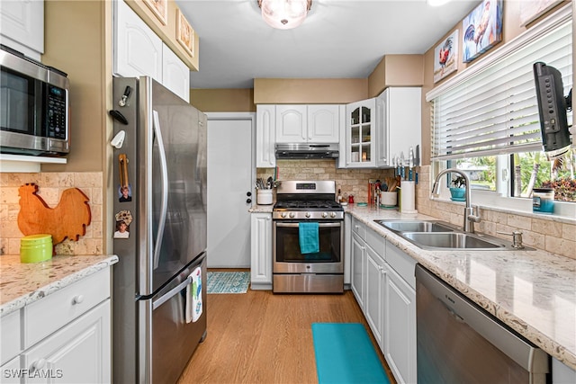 kitchen featuring white cabinets, sink, decorative backsplash, light hardwood / wood-style floors, and stainless steel appliances