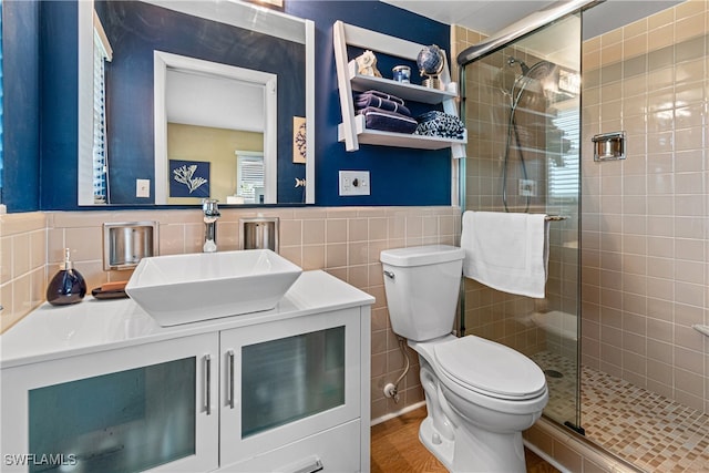 bathroom featuring walk in shower, vanity, toilet, and tile walls