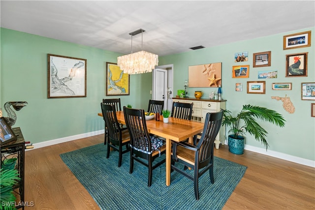 dining space with light wood-type flooring and a chandelier