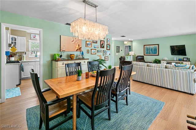 dining area with light hardwood / wood-style flooring and a notable chandelier