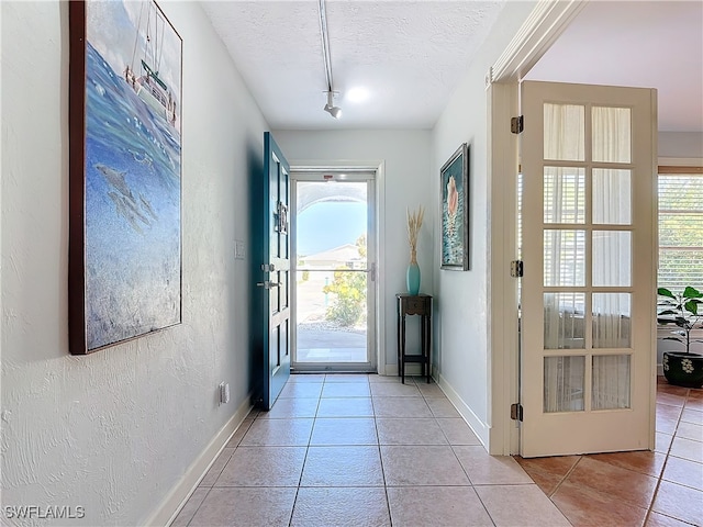 entryway featuring a wealth of natural light, light tile patterned flooring, and a textured ceiling