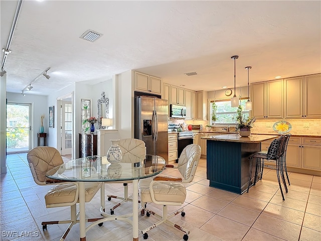 tiled dining area featuring a textured ceiling, track lighting, and sink