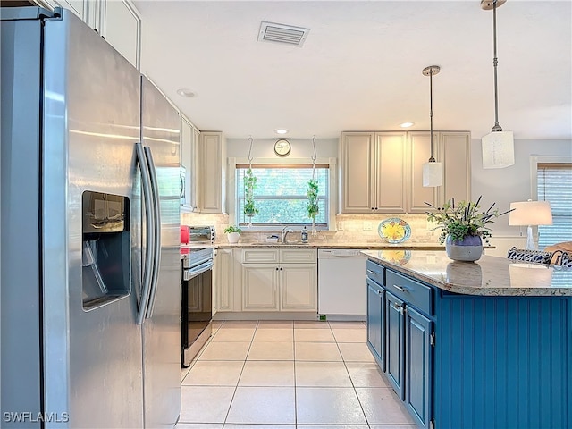 kitchen with light stone countertops, backsplash, stainless steel appliances, pendant lighting, and light tile patterned flooring