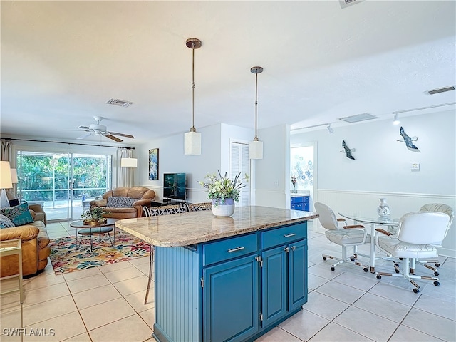 kitchen featuring a breakfast bar, ceiling fan, blue cabinetry, decorative light fixtures, and light tile patterned flooring