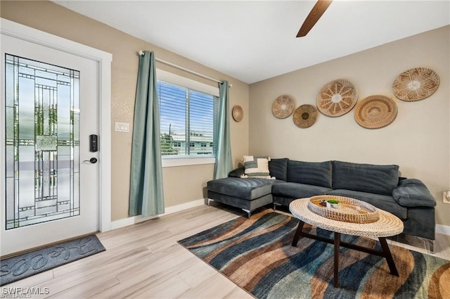 living area featuring baseboards, a ceiling fan, and light wood-style floors