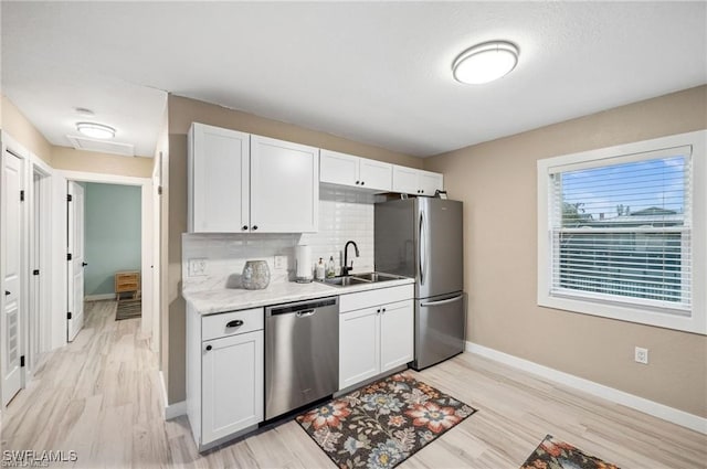 kitchen featuring stainless steel appliances, a sink, light countertops, and white cabinets