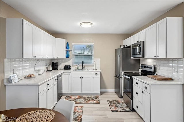 kitchen with sink, stainless steel appliances, light stone countertops, decorative backsplash, and white cabinets