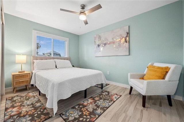 bedroom with ceiling fan, baseboards, and wood finished floors