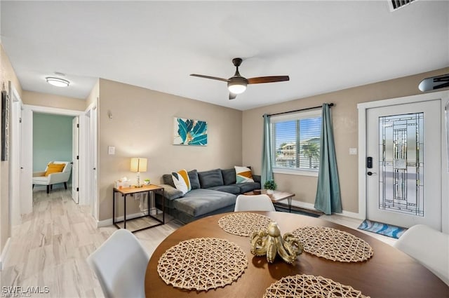 living area with a ceiling fan, baseboards, and light wood finished floors