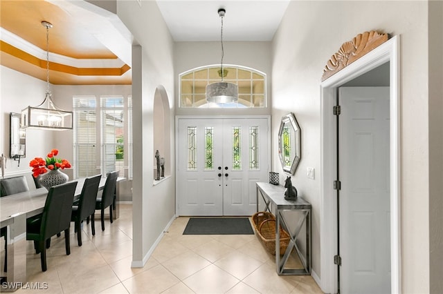 tiled entryway with a notable chandelier and crown molding