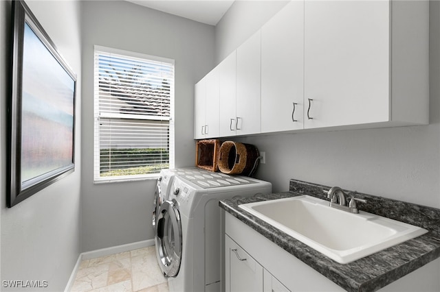 clothes washing area with washing machine and dryer, a wealth of natural light, sink, and cabinets