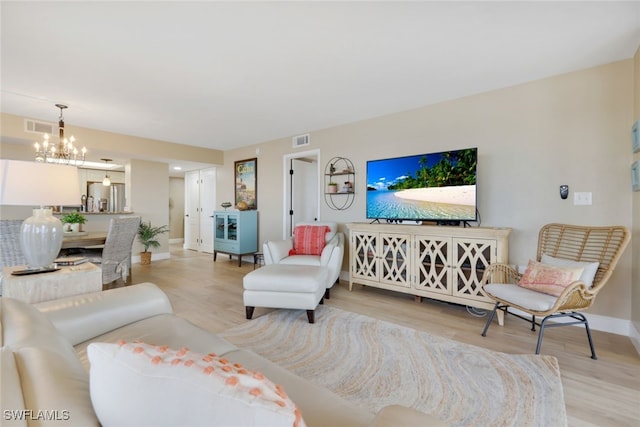 living room with light hardwood / wood-style floors and a notable chandelier