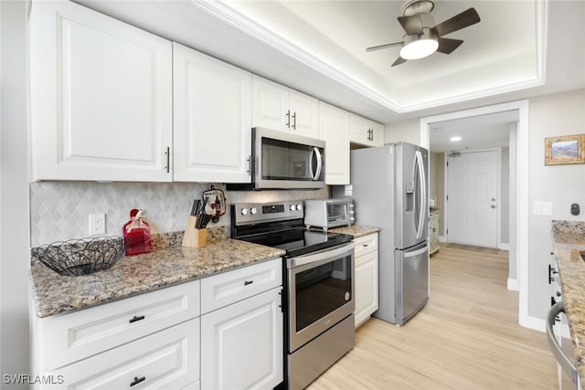 kitchen with white cabinets, appliances with stainless steel finishes, light wood-type flooring, and a raised ceiling