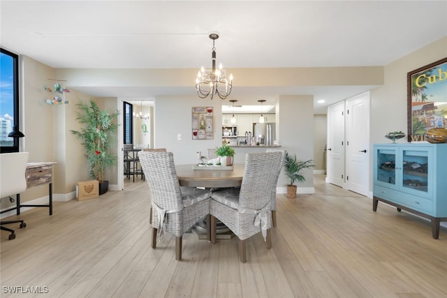 dining room with light hardwood / wood-style flooring and a notable chandelier