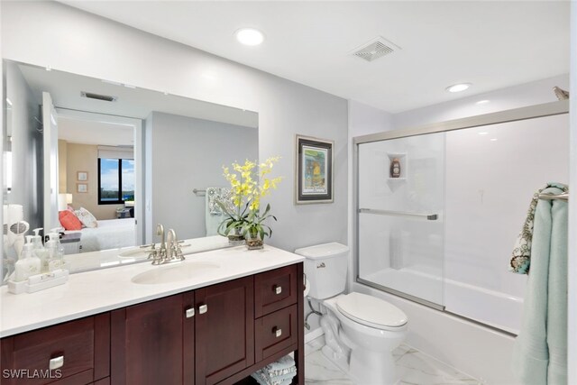 full bathroom featuring vanity, toilet, and shower / bath combination with glass door