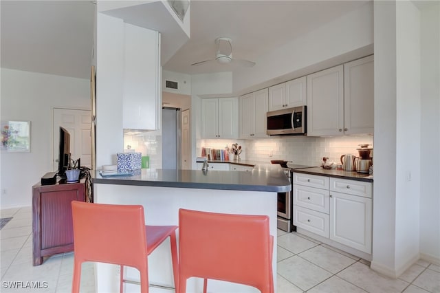 kitchen with backsplash, white cabinets, stainless steel appliances, and light tile patterned floors