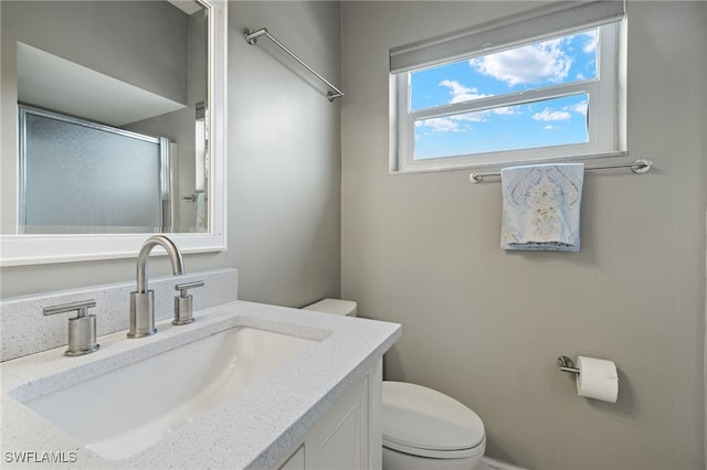 bathroom featuring vanity, toilet, and walk in shower