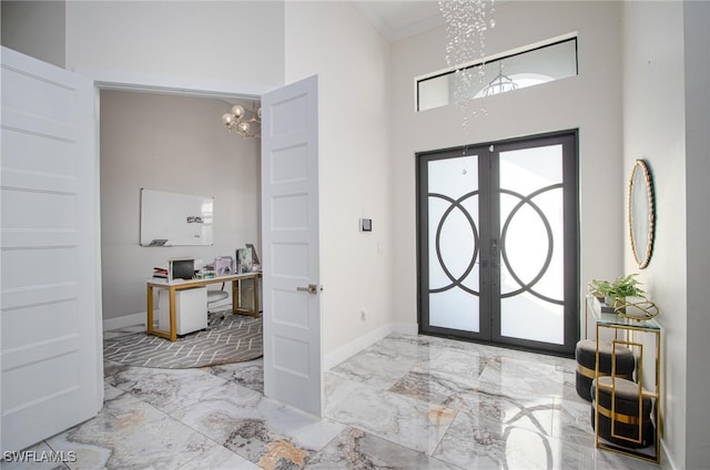 foyer featuring a chandelier, french doors, ornamental molding, and a high ceiling