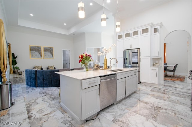 kitchen featuring appliances with stainless steel finishes, sink, pendant lighting, a center island with sink, and white cabinetry