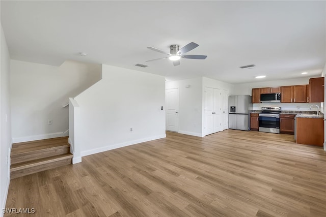 unfurnished living room with light wood-type flooring, ceiling fan, and sink