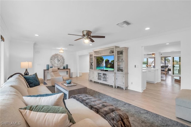 living room featuring light hardwood / wood-style floors, ceiling fan, and crown molding