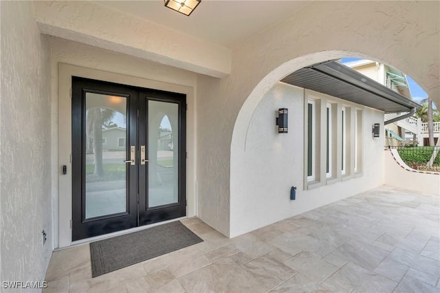 view of exterior entry with french doors and a patio area