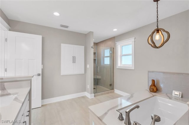 bathroom with vanity and shower with separate bathtub