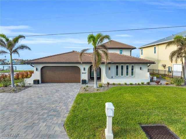 view of front of property with a garage, a front lawn, and a water view