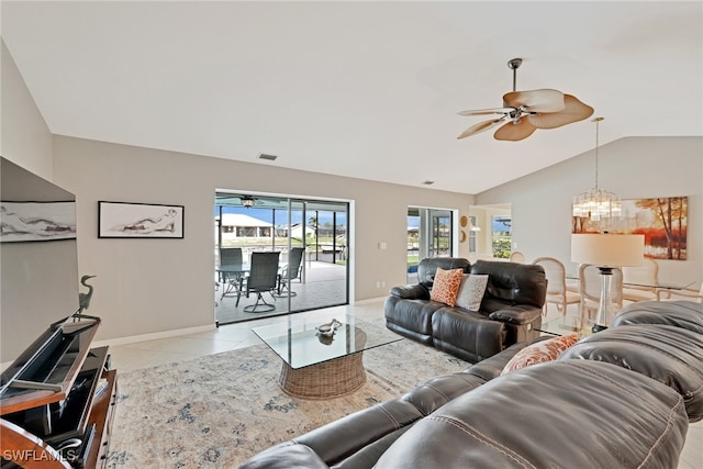 tiled living room with ceiling fan with notable chandelier and lofted ceiling