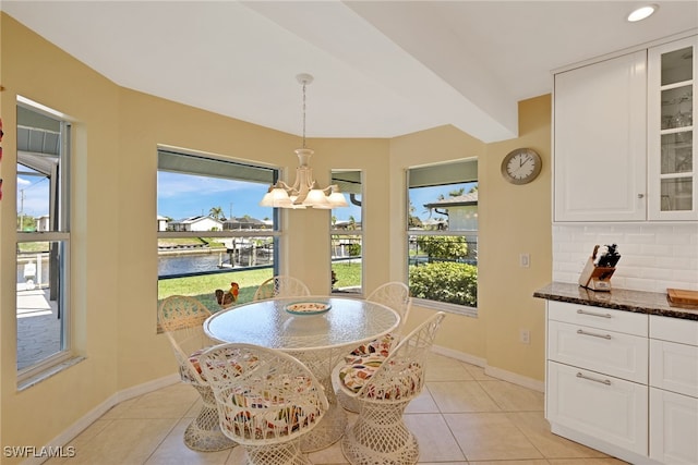 dining area with a water view, light tile patterned flooring, and a notable chandelier