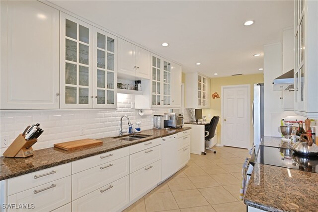 kitchen with dark stone countertops, white cabinetry, sink, and stainless steel appliances