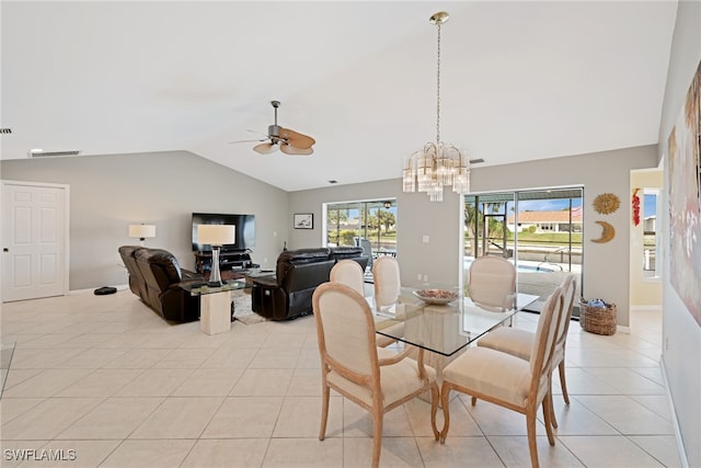 tiled dining room with plenty of natural light, ceiling fan with notable chandelier, and lofted ceiling