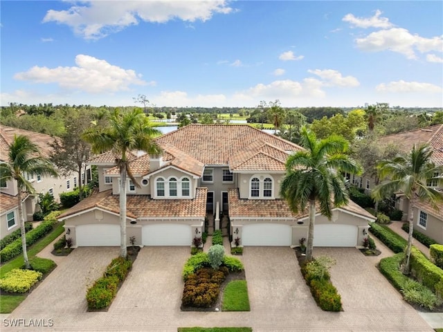 mediterranean / spanish-style home with a tiled roof, decorative driveway, and stucco siding