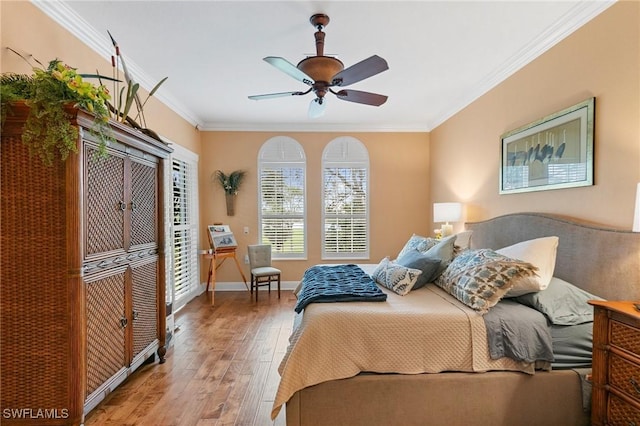 bedroom with a ceiling fan, wood finished floors, crown molding, baseboards, and access to exterior