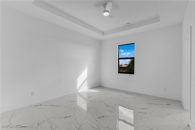 spare room featuring a raised ceiling and ceiling fan