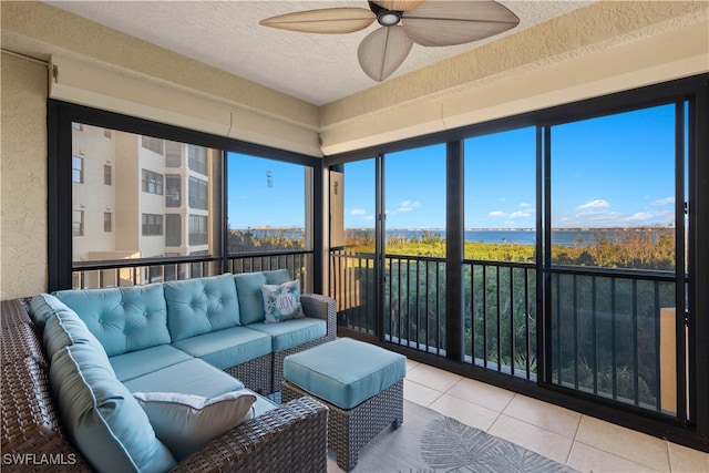 sunroom with ceiling fan and a water view