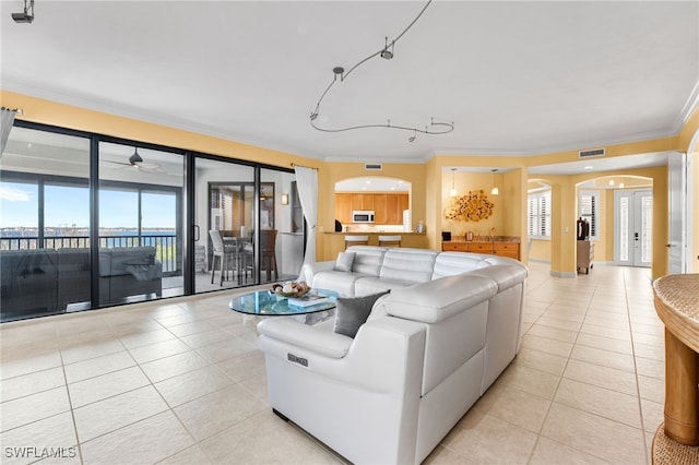 tiled living room with plenty of natural light, crown molding, and ceiling fan