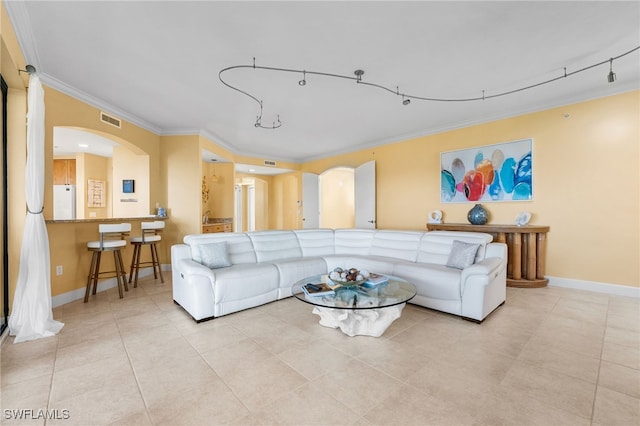 living room with light tile patterned floors, baseboards, visible vents, arched walkways, and ornamental molding