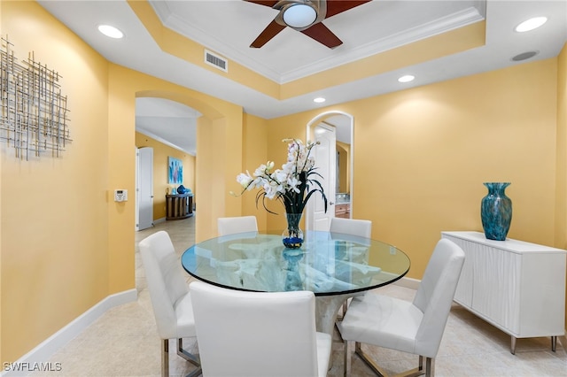 dining space with ceiling fan, crown molding, and a tray ceiling