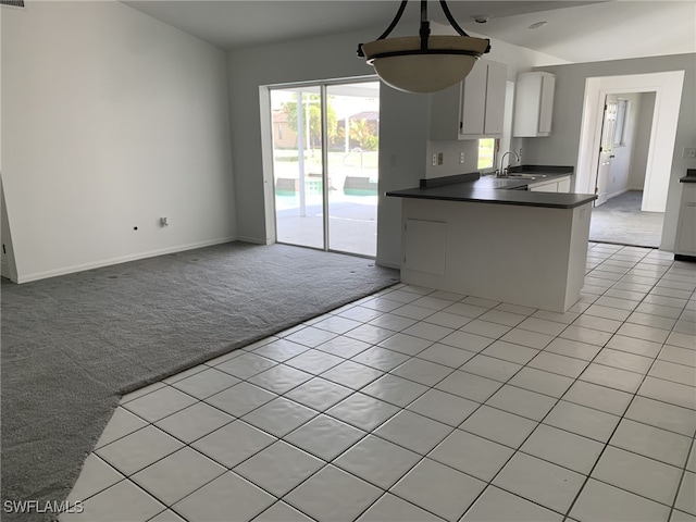 kitchen featuring kitchen peninsula, white cabinetry, hanging light fixtures, and light carpet