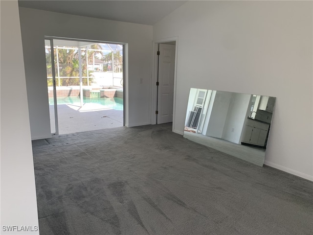 carpeted empty room featuring vaulted ceiling