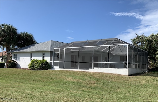 back of property with glass enclosure and a lawn