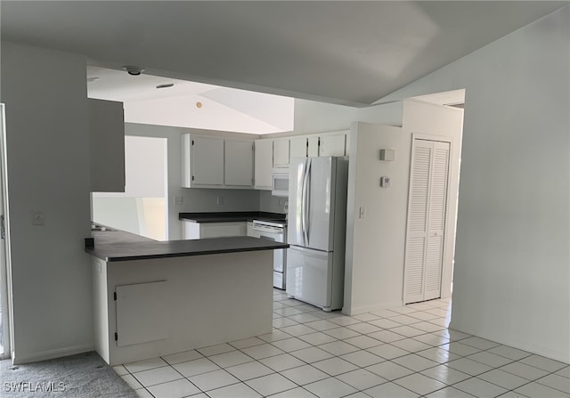 kitchen featuring white appliances, white cabinets, vaulted ceiling, light tile patterned floors, and kitchen peninsula