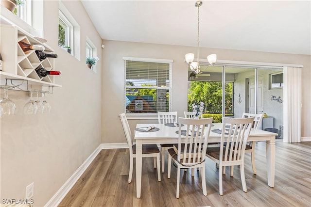 dining room featuring light wood-style floors, baseboards, and an inviting chandelier