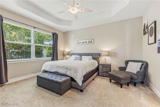 carpeted bedroom with a ceiling fan, a raised ceiling, and baseboards