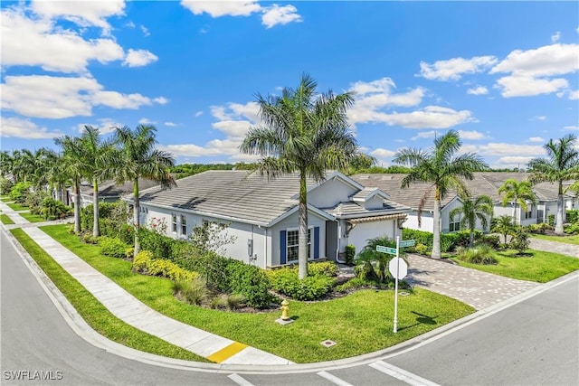 single story home with decorative driveway, a front yard, a tile roof, and stucco siding