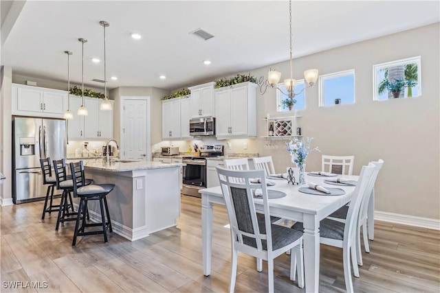 kitchen featuring visible vents, an island with sink, a breakfast bar, stainless steel appliances, and a sink