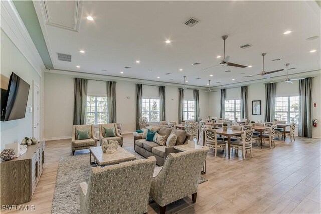 living area featuring attic access, visible vents, ornamental molding, and light wood finished floors