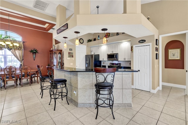 kitchen featuring white cabinets, light tile patterned floors, stainless steel appliances, and a breakfast bar area